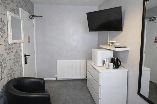 a room with a chair and a tv on the wall at The Roslyn Guest House in Paignton