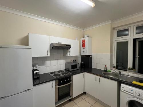 a kitchen with white cabinets and a black counter top at Cosy Budget Rooms in Camden Town near Regents Park in London