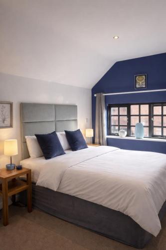 a bedroom with a large bed with blue walls at The Three Horseshoes Boutique Rooms in Dunstall