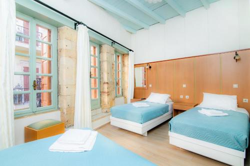 two beds in a room with two windows at Alegria Pension in Chania