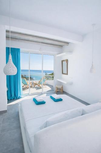 a white living room with a large bed and a large window at Poseidon Blue Gastronomy Hotel in Afiartis