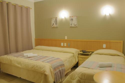 a hotel room with two beds and a table at Hotel Montana Serra Negra in Serra Negra