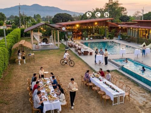 a group of people sitting at tables next to a pool at Wisdom Park Pattaya near Tomorrowland Thailand in Ban Khao Mai Kaeo