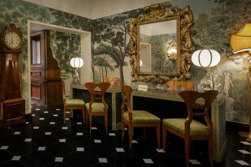 a room with a mirror and chairs and a clock at Hotel d’Inghilterra Roma – Starhotels Collezione in Rome