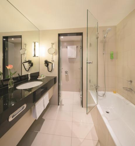 a bathroom with a tub and a sink and a shower at Mövenpick Hotel Egerkingen in Egerkingen