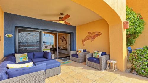 a patio with a blue couch and two chairs at Ground Floor 2BR Beachfront - Steps to Pool - Princesa E104 - BeachBumCondos in Puerto Peñasco