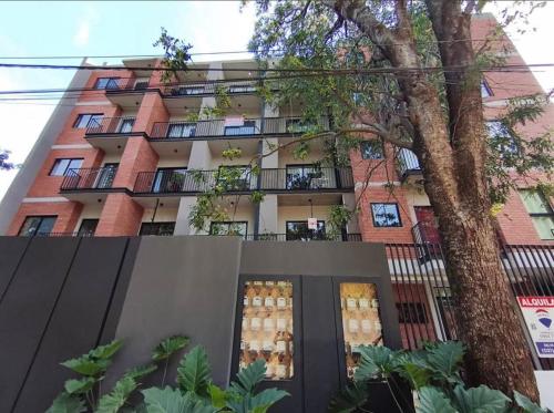 an apartment building with a tree in front of it at Modern Studio with Balcony in Asunción