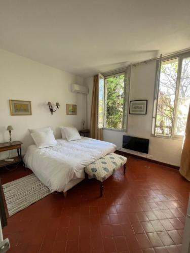 a bedroom with a large white bed and two windows at Face au Palais in Avignon