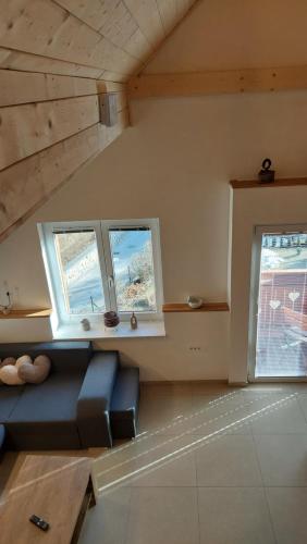 a living room with a couch and three windows at Apartments Ela in Rateče