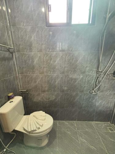 a bathroom with a white toilet and a window at Son House in Ban Thalat Choeng Thale