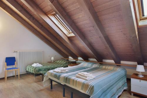 two beds in a room with wooden ceilings at La polse di San Pieri in Zuglio