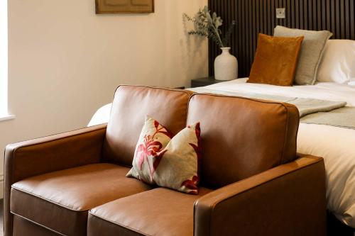 a brown leather couch sitting next to a bed at Lovely Studio Flat on Bath Road - Flat 8 in Bristol