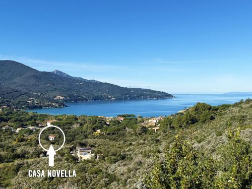 a lighthouse on a hill next to a body of water at Casa Novella - Argonauti Vacanze in Procchio