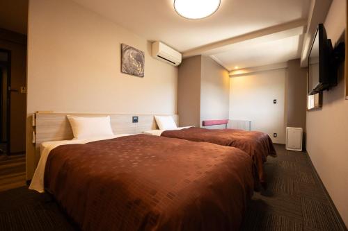 a hotel room with two beds and a television at Sun Hotel Kudamatsu in Hanaoka