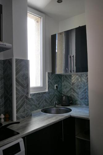 a kitchen with a sink and a window at Chocolat Paris, Cozy apartment in Levallois-Perret