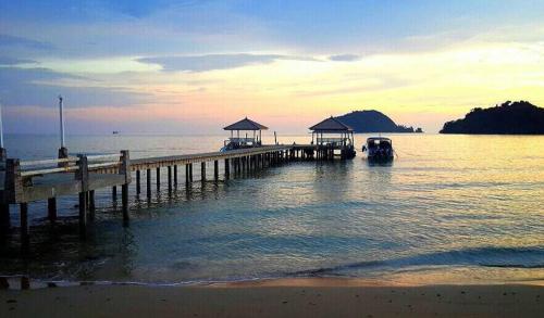 a pier with a boat in the water at Makathanee Resort in Ko Mak