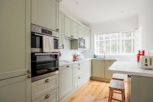 a kitchen with white cabinets and a stove top oven at Primrose - Refurbished Family Home, With Rear Garden in Poole