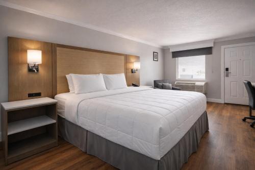 a hotel room with a large white bed and a window at Destin Inn & Suites in Destin
