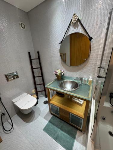 a bathroom with a sink and a toilet and a mirror at T1 Praia Areia Branca in Lourinhã