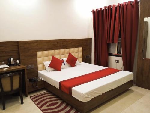 a bedroom with a bed with red curtains and a desk at Hotel New M I Plaza in Gaya