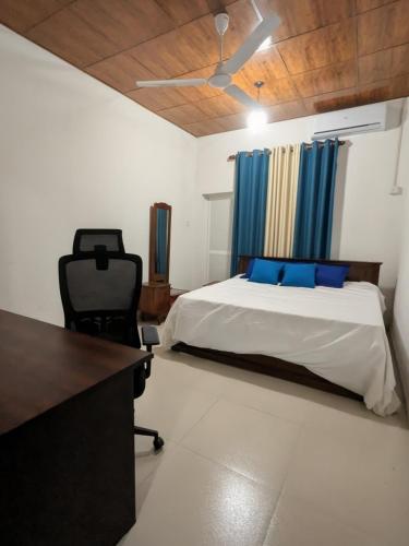 a bedroom with a bed with blue pillows and a desk at Prince Cottage - Entire Private Cottage in Kesbewa