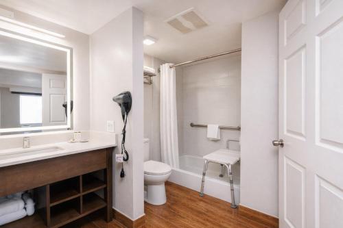 a bathroom with a sink and a toilet and a mirror at Destin Inn & Suites in Destin