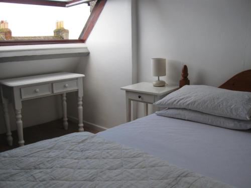 ペンザンスにあるTrezise Cottageのベッドルーム1室(ベッド1台、テーブル2台、窓付)
