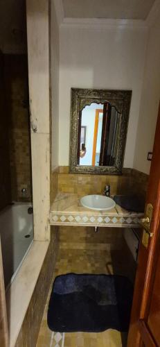 a bathroom with a sink and a mirror and a tub at Chic Palm Grove Apartment Pool View in Marrakesh