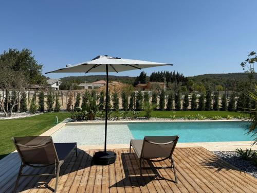 a patio with two chairs and an umbrella next to a pool at Kırmızı Bağ Resort in Kuscular