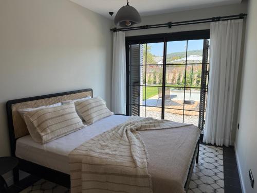a bedroom with a bed and a large window at Kırmızı Bağ Resort in Kuscular
