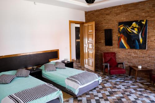 ein Schlafzimmer mit zwei Betten, einem Stuhl und einem Gemälde in der Unterkunft Ims'Chill Hotel in Imsouane