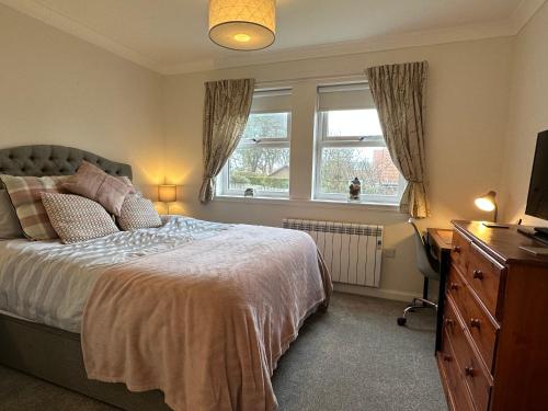 a bedroom with a bed and a television and a dresser at Brada View - Bamburgh, Northumberland in Bamburgh