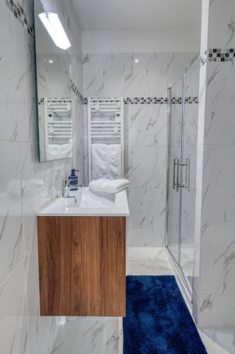 a white bathroom with a sink and a shower at Le Jardin de Lili - Disney 30 min - Clim & Wifi in Germigny-lʼEvêque