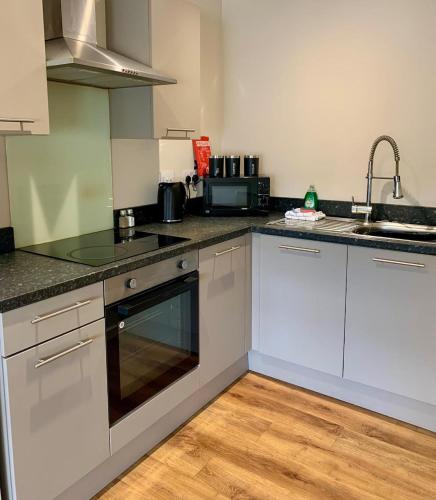 a kitchen with white cabinets and a sink at 1BR Flat By Cozy Quarters Property Management Short Term Rental Hartlepool Near Marina Views in Hartlepool