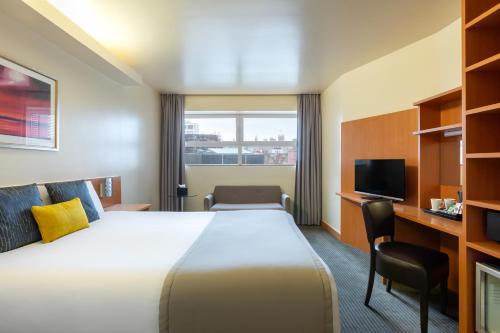a hotel room with a large bed and a tv at STG Hotel Oxford Street - formerly St Giles London Hotel in London