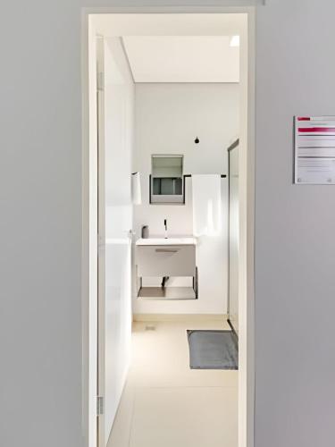 a white bathroom with a sink and a mirror at Studio IV Jundiaí - Com Ar Condicionado in Jundiaí