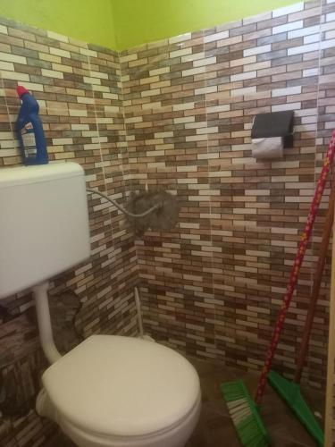 a bathroom with a white toilet and a brick wall at ADONAI homes in Malindi