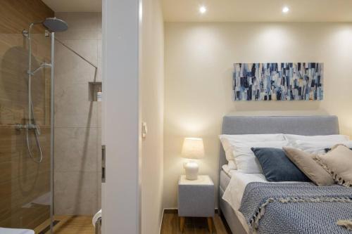 a bedroom with a bed and a glass shower at New Luxury Villa Korcula Timeless with private pool, Free Parking, Seafront, for 6 persons in Korčula