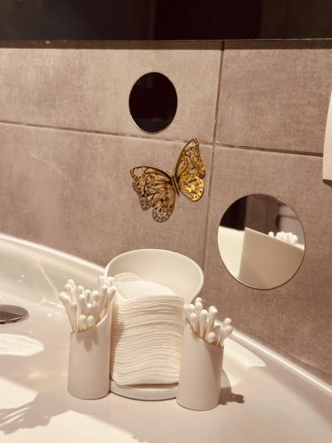 ein Badezimmer mit Waschbecken, Handtüchern und Schmetterlingen in der Unterkunft Vila Ema Râşnov in Râșnov