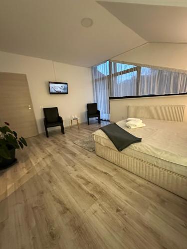 ein Schlafzimmer mit einem Bett und zwei Stühlen in der Unterkunft Vila Ema Râşnov in Râșnov