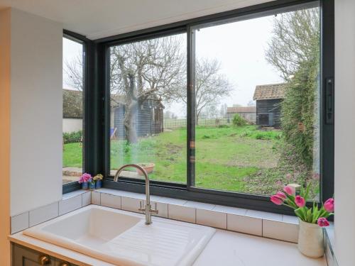 a kitchen sink with a window looking out at a yard at The Old Smithy in Cambridge