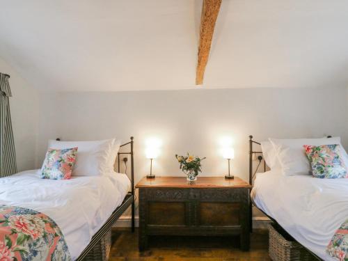 two beds in a room with two lamps on a table at The Old Smithy in Cambridge