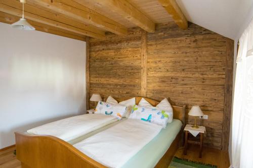a bed in a room with a wooden wall at Biohof Schmidbauer in Frankenburg