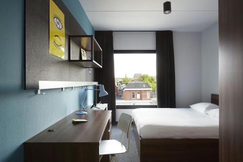 a hotel room with a bed and a desk and a window at The Social Hub Groningen in Groningen