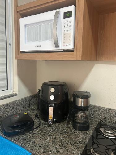 a kitchen counter with a coffee maker and a microwave at Studio J&C 01 in Primavera do Leste