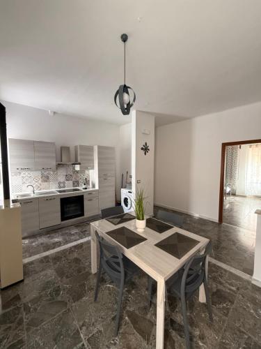 a dining room with a table and a kitchen at Carmen House in Bernalda