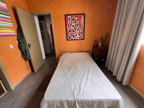 a bed in a room with an orange wall at Ap decorado Setor Bueno in Água Boa