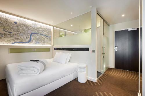 a white bed in a room with a map on the wall at hub London - King's Cross in London