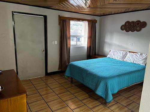 a bedroom with a blue bed and a window at hotel Rarámuri in Creel