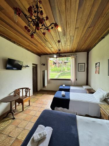 a bedroom with three beds and a large window at Capricho Asturiano in Santo Antônio do Leite